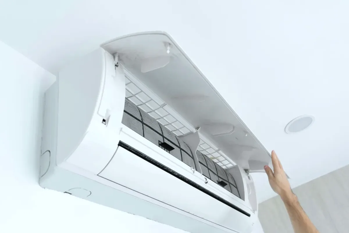 Hand opening the cover of a wall-mounted ductless air conditioner